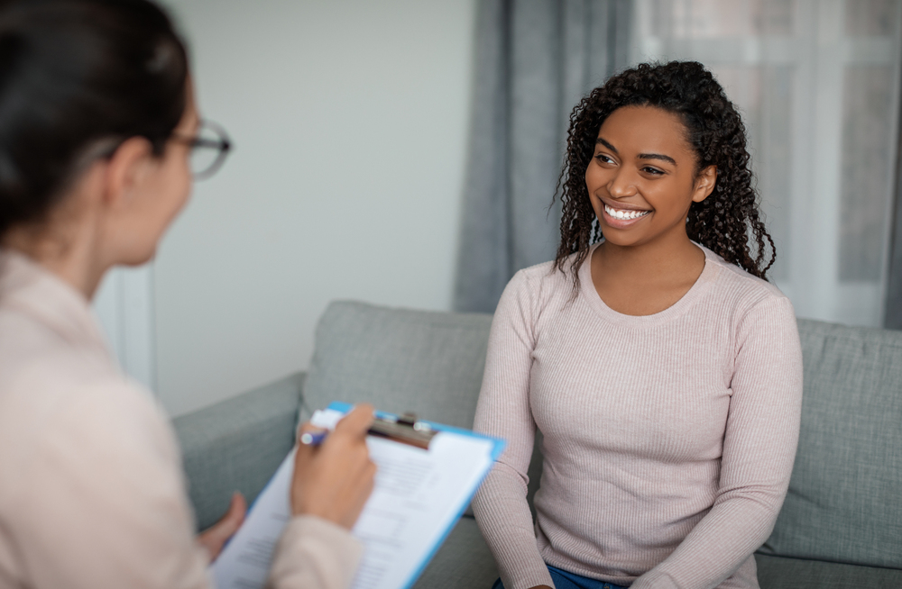 young woman and veteran in therapy happy that her Optum VA CCN mental health rehab insurance covers treatment