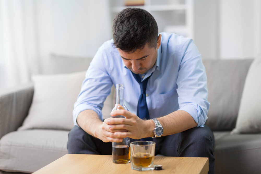 Alcoholic with bottle drinking whiskey at home